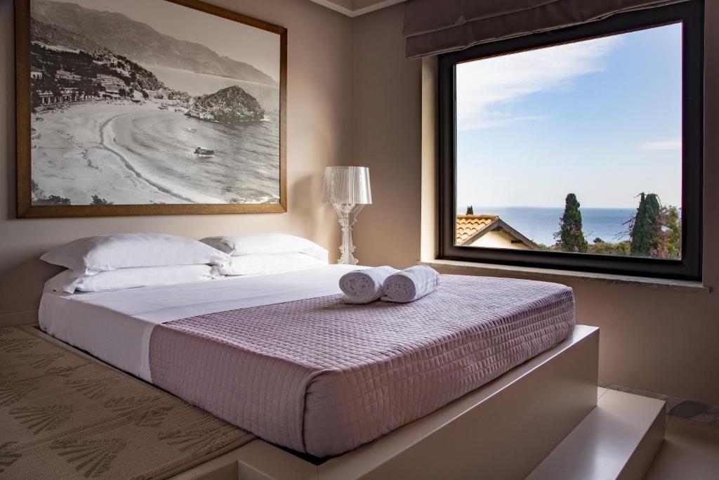 een slaapkamer met een bed en een groot raam bij Fenetre sur le blue in Taormina