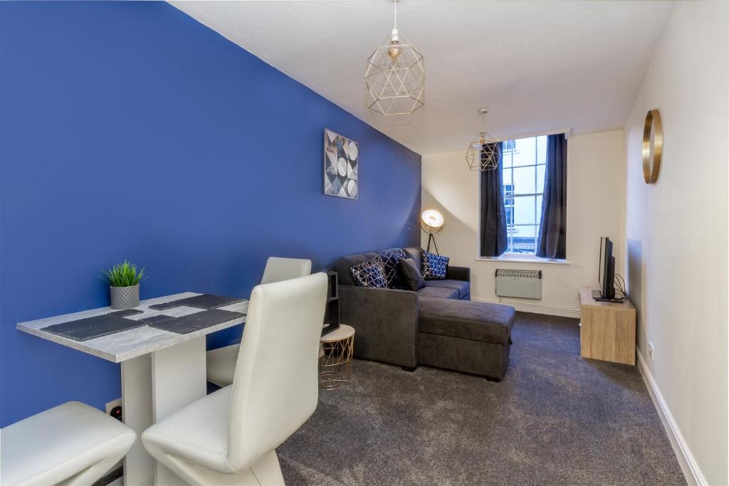 a living room with blue walls and a table and chairs at Guest Homes - New Street Suite in Worcester