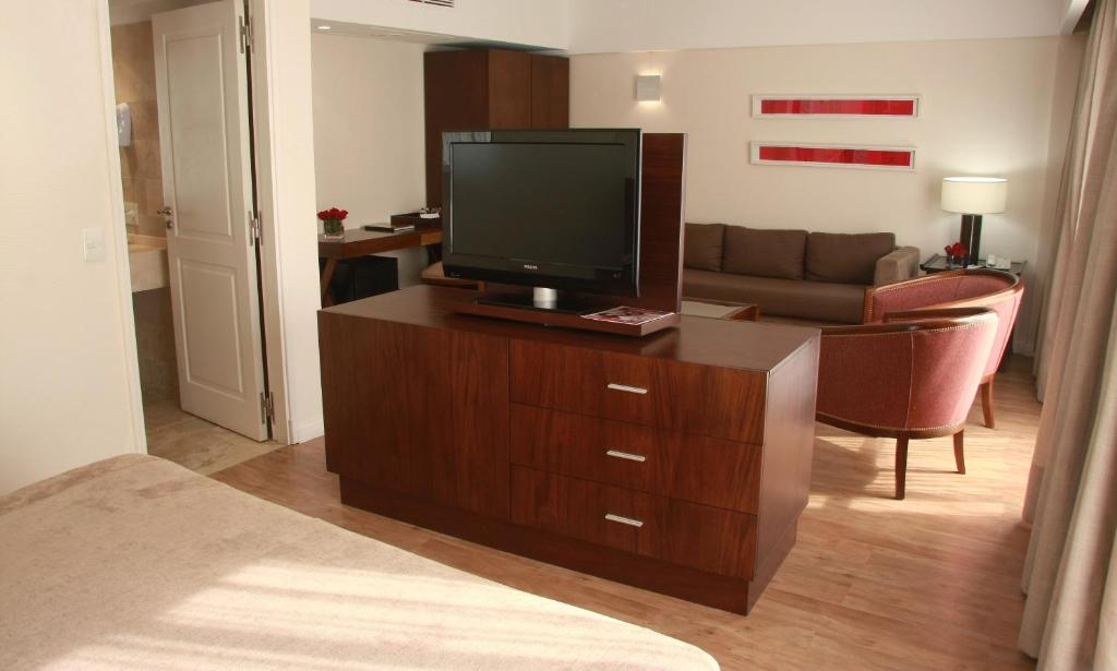 a living room with a television on a wooden dresser at Grand King Hotel in Buenos Aires