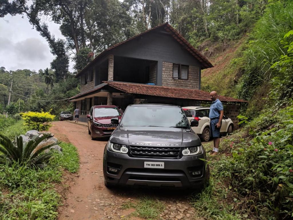 a car parked on a dirt road in front of a house at Kwality Estate in Madikeri