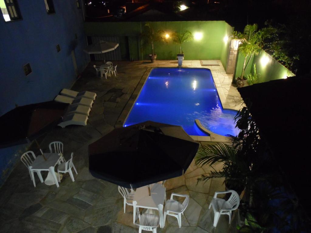 una piscina por la noche con sillas y una mesa en Pousada Casebre, en Pirenópolis