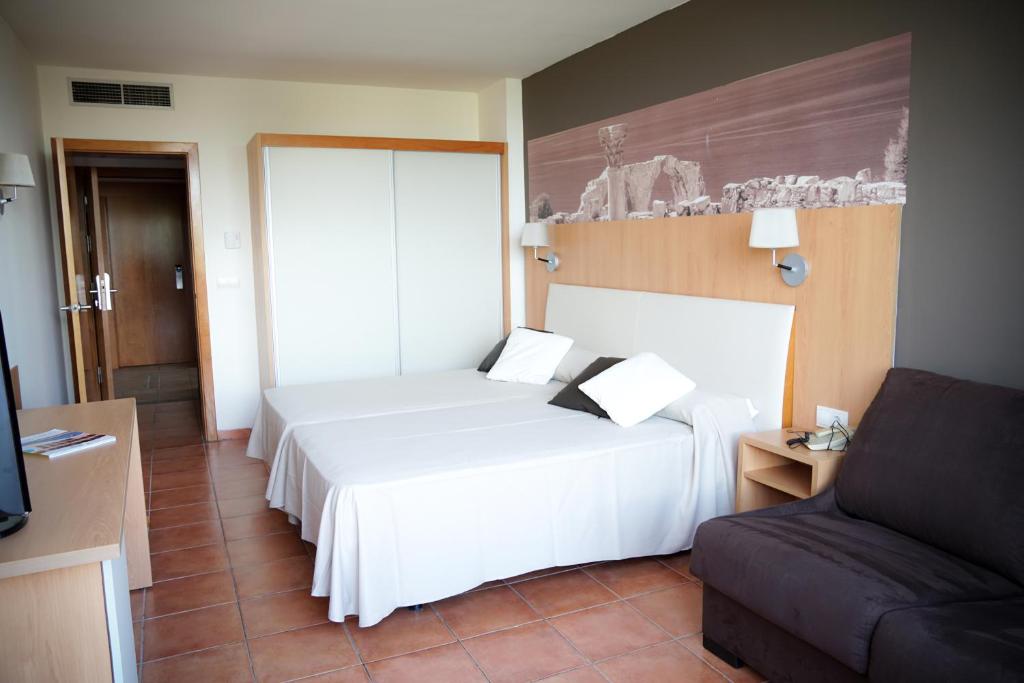 Habitación de hotel con cama blanca y sofá en Ohtels Vil·la Romana, en Salou