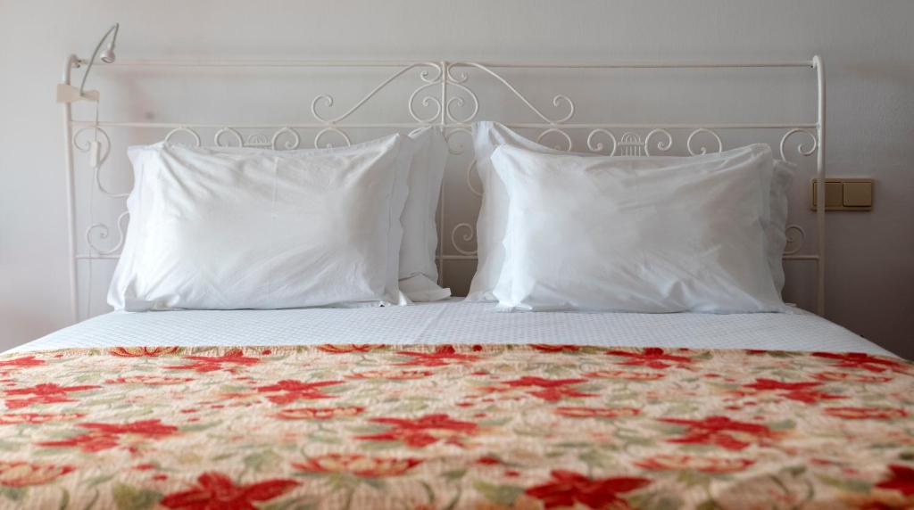 a bed with white pillows and red flowers on it at Quinta das Buganvílias in Castelo Branco