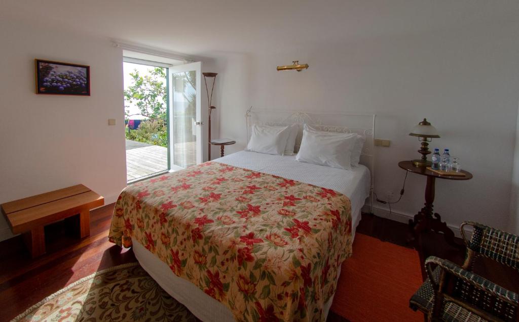 a bedroom with a bed with a floral bedspread at Quinta das Buganvílias in Castelo Branco