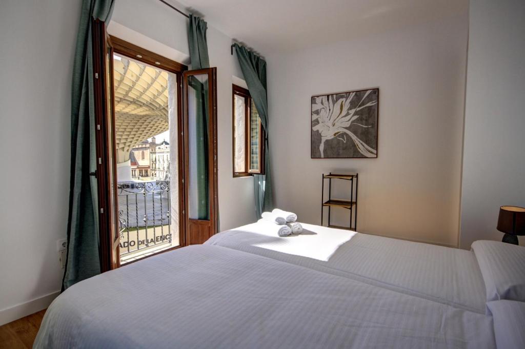 a bedroom with a white bed and a window at Apartamentos Setas Center in Seville