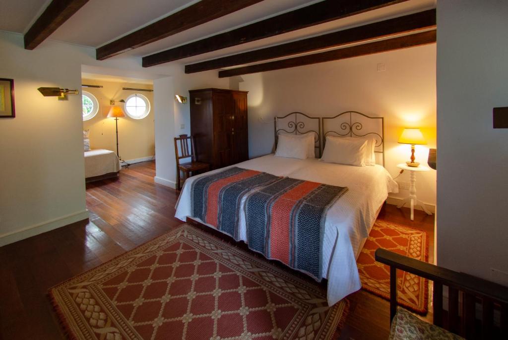 a bedroom with a large bed and a living room at Quinta das Buganvílias in Castelo Branco