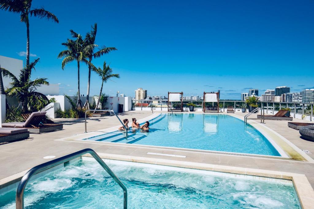a swimming pool with two people in it with the ocean at Ivory On The Bay in Miami Beach
