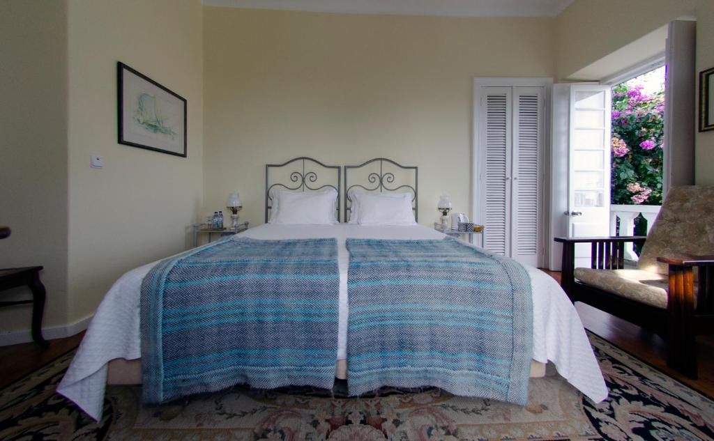 a bedroom with a bed with a blue and white blanket at Quinta das Buganvílias in Castelo Branco