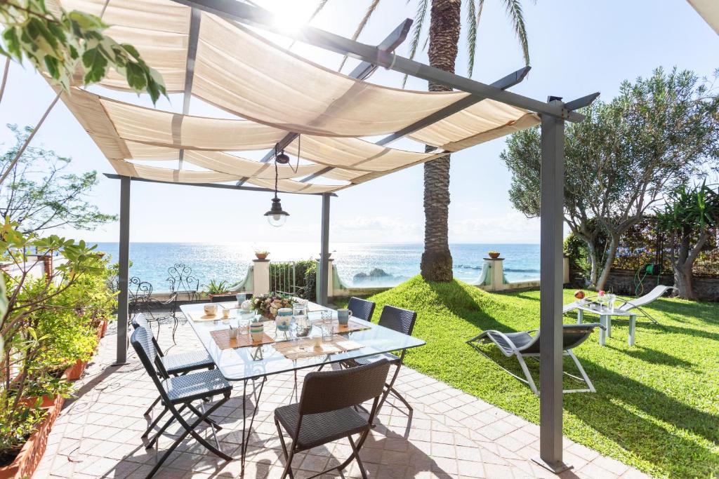 patio ze stołem i krzesłami z widokiem na ocean w tle w obiekcie Penelope Seaview Apartment w Katanii