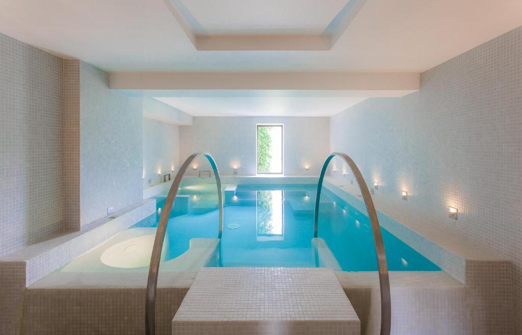 a bathroom with a blue pool with a bench in it at Baumanière - Les Baux de Provence in Les Baux-de-Provence