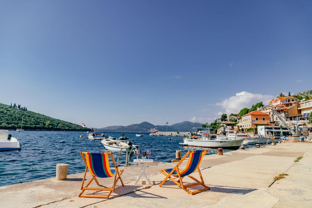two chairs sitting on a dock near the water with boats at Apartments Bigovo Veljic in Tivat
