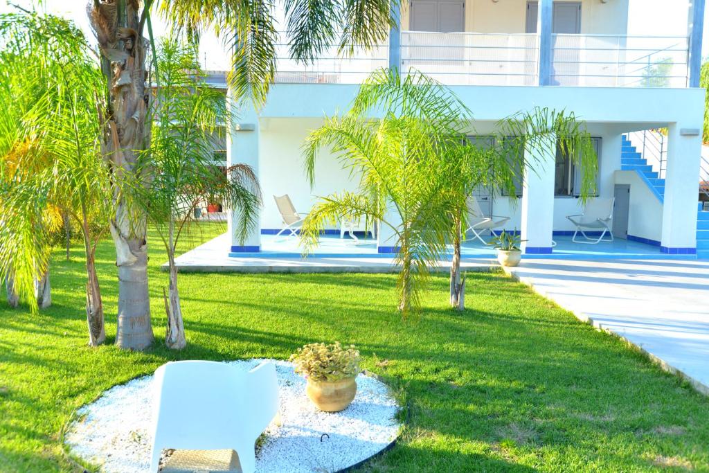 a yard with palm trees and a white building at VillaColì Menfi in Menfi