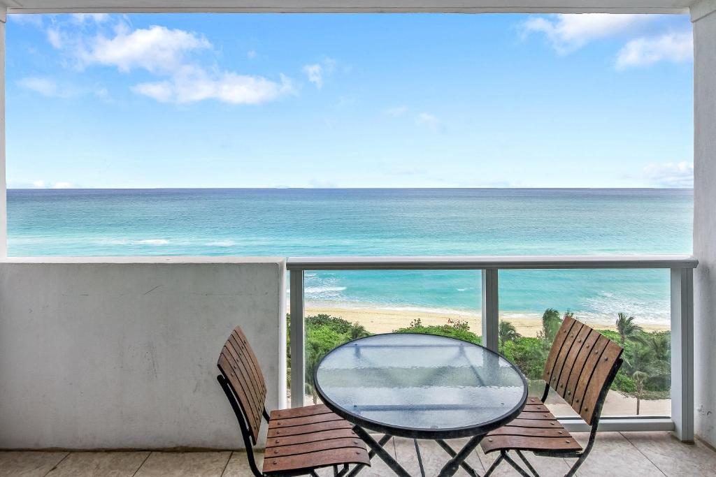 een glazen tafel en 2 stoelen op een balkon met uitzicht op de oceaan bij Oceanfront views, balcony & gym, bars, beach access and free parking! in Miami Beach