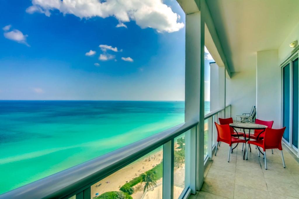 uma varanda com uma mesa e cadeiras e o oceano em Gorgeous Oceanfront Penthouse with gym, bars, beach access and free parking! em Miami Beach