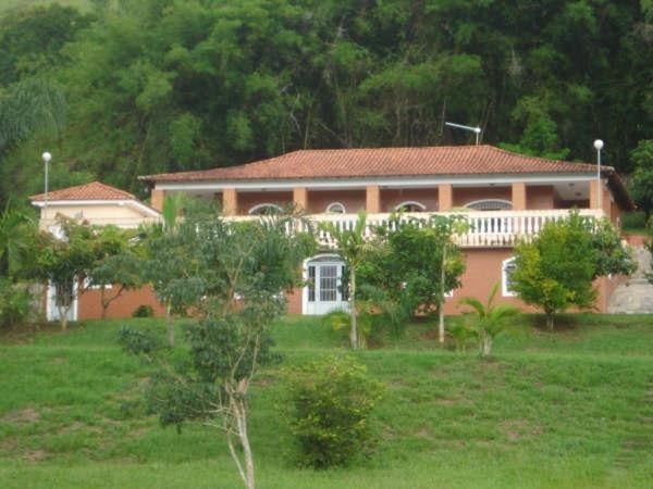 uma casa num campo com árvores à frente em Chácara Paraíso de Itamonte MG em Itamonte