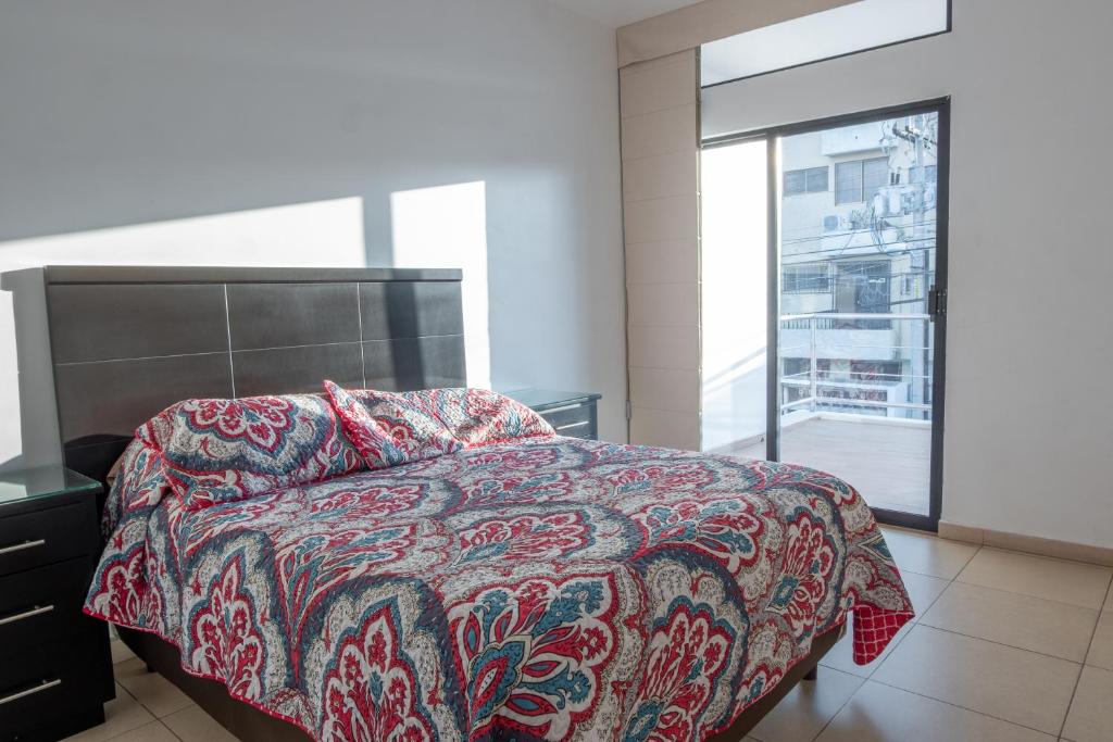 1 dormitorio con cama y ventana grande en Apartamentos Torre II Condominios - Pet Friendly, en Mazatlán