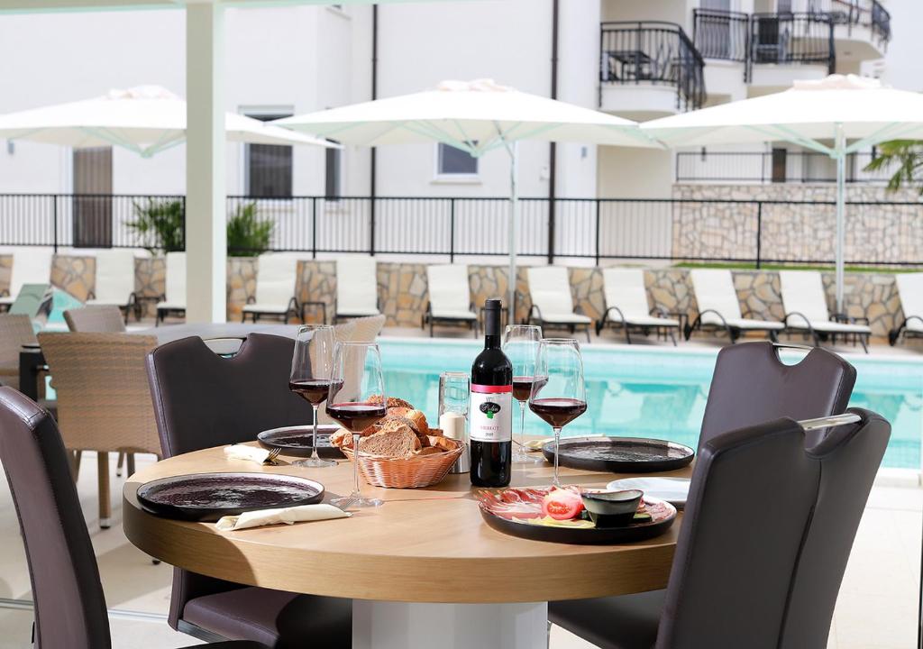 a table with a bottle of wine and wine glasses at Cool Šilo Appartement Resort in Šilo