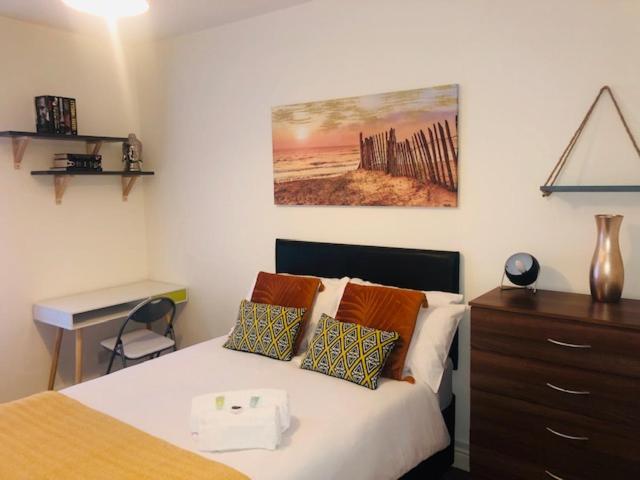 a bedroom with a bed with a desk and a painting on the wall at Budget Rooms @ Underwood Lane Crewe in Crewe