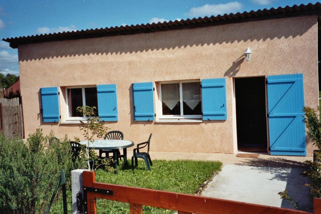 ein Haus mit blauen Fensterläden und einem Tisch im Hof in der Unterkunft Gite de Pêche in Pont-de-Poitte