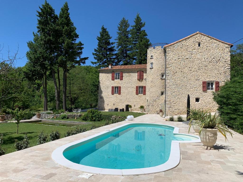 une maison avec une piscine en face d'un bâtiment dans l'établissement Chateau de la Rode, à Aumessas