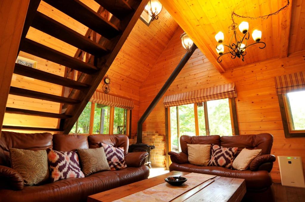 a living room with leather couches and a wooden ceiling at Log sweet Villa YU.CABIN / Vacation STAY 5351 in Inawashiro