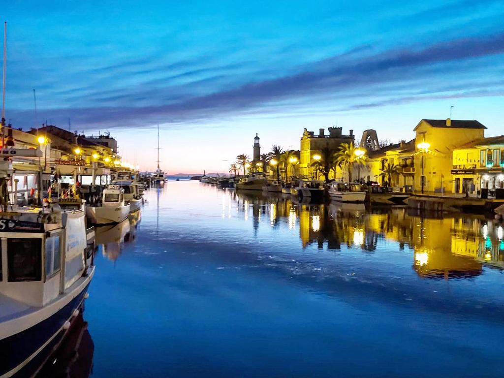 a harbor with boats in the water at night at Studio 237 Port Camargue, Piscine, Climatisation, 2 personnes in Le Grau-du-Roi