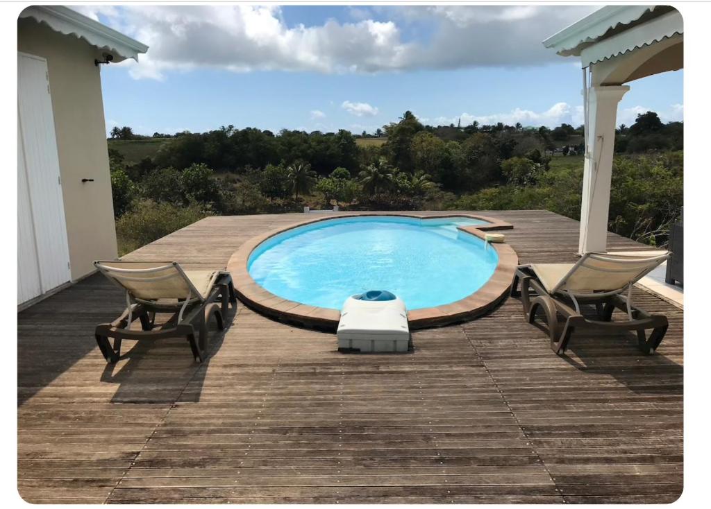 a swimming pool on a wooden deck with two chairs at Loft Paradis in Sainte-Anne