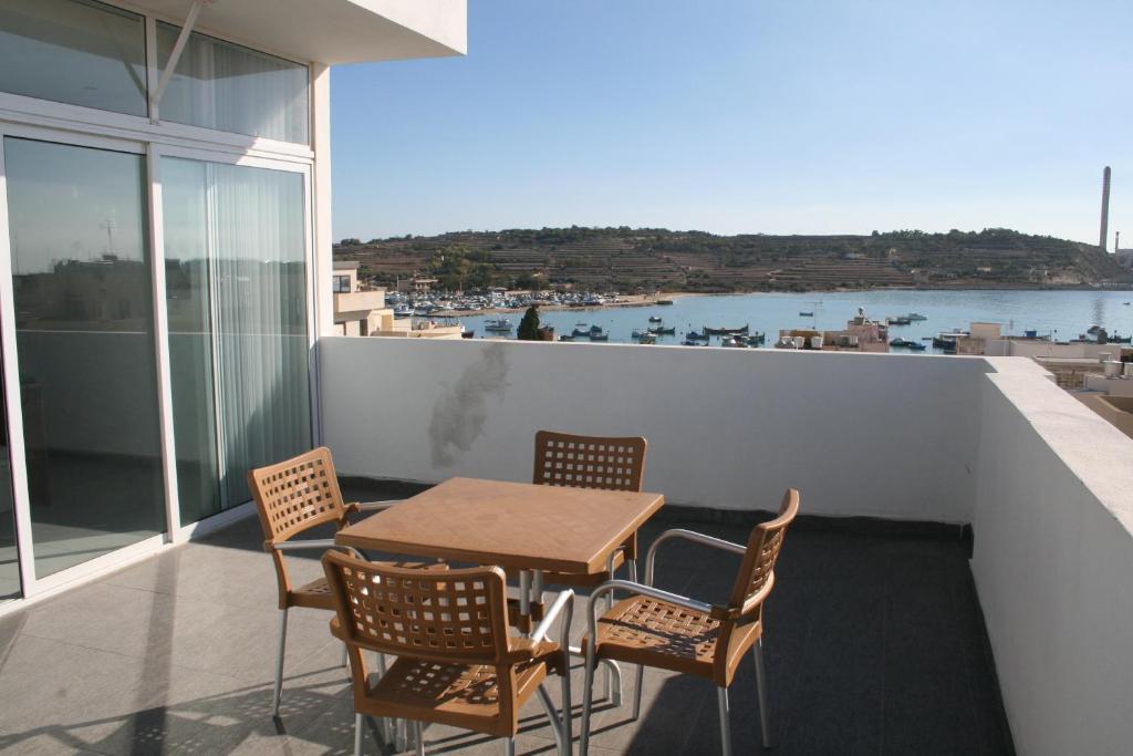 uma mesa e cadeiras numa varanda com vista para a água em Harbour Lodge em Marsaxlokk