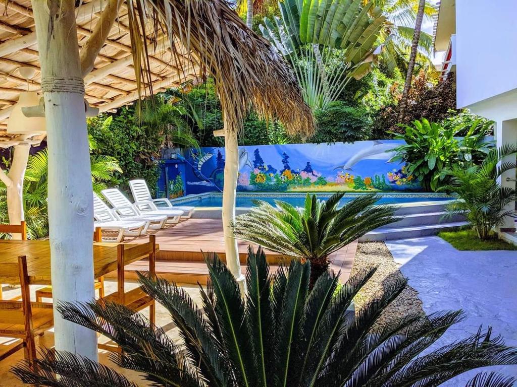 Casa Brisa Mar Hotel في لاس تاريناس: منتجع به مسبح وبه كراسي واشجار نخيل