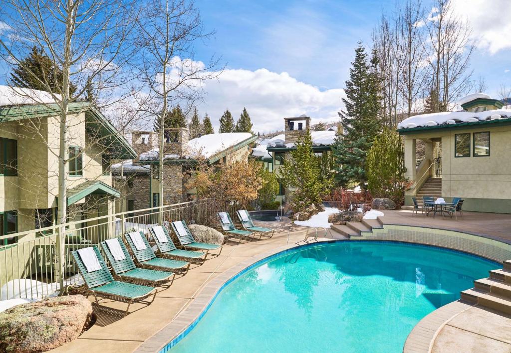 una piscina con sedie a sdraio accanto a una casa di Tamarack Townhomes - CoralTree Residence Collection a Snowmass Village