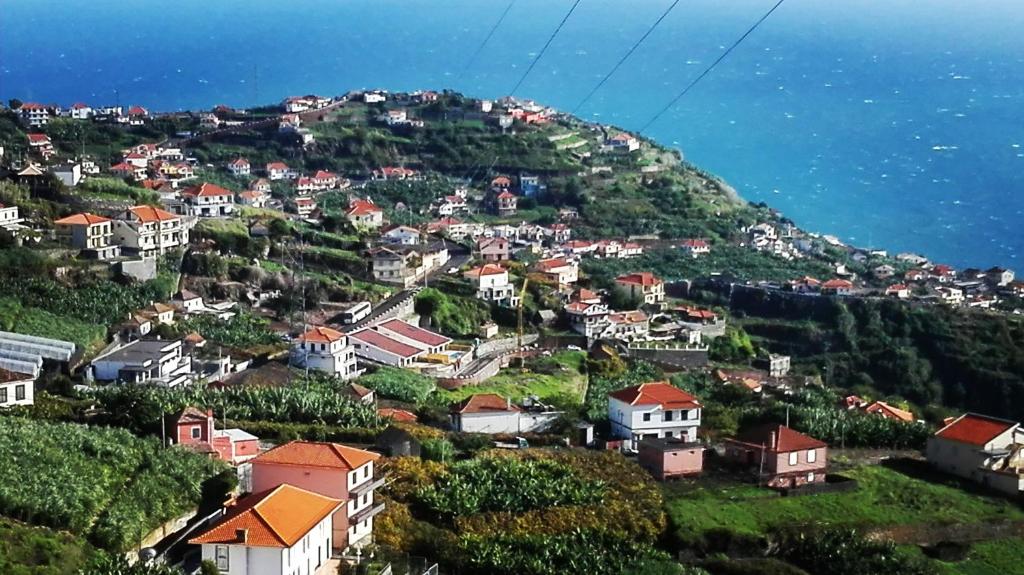 un village sur une colline avec des maisons et l'océan dans l'établissement Apartamento Villa, à Ponta do Sol