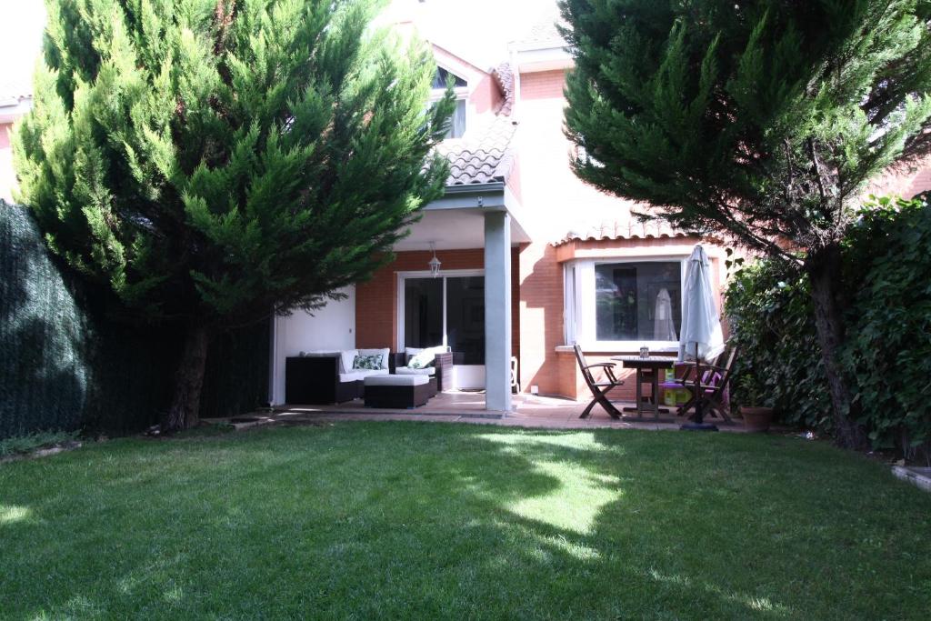 une cour avec de l'herbe et des arbres verdoyants et une maison dans l'établissement Chalet Aldeamayor Golf VUT 47-269, à El Cardiel