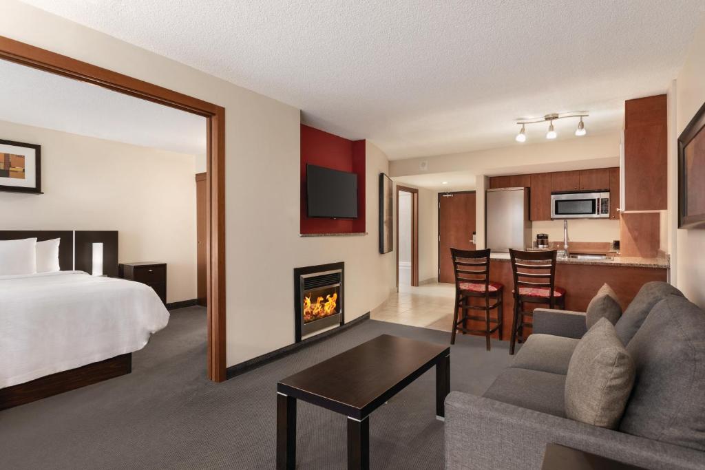 - une chambre avec un lit et un salon avec une cheminée dans l'établissement Embassy Suites by Hilton - Montreal, à Montréal