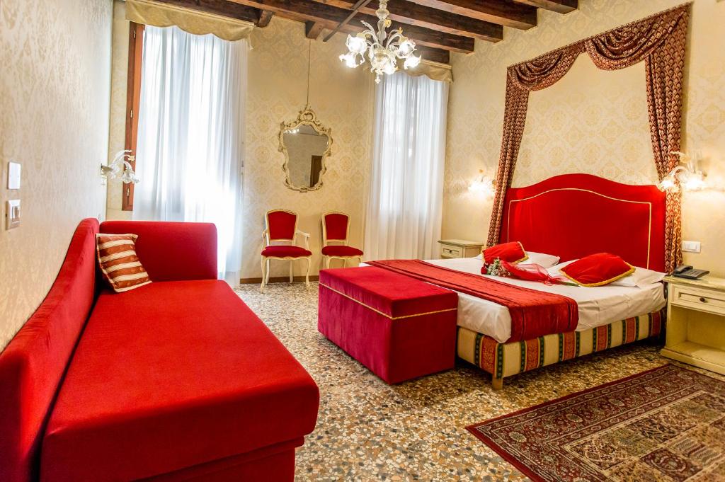 1 dormitorio con cama roja, sofá y espejo en Residenza La Campana, en Venecia