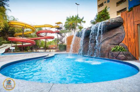 a swimming pool with a waterfall in a resort at Golden Dolphin Express in Caldas Novas