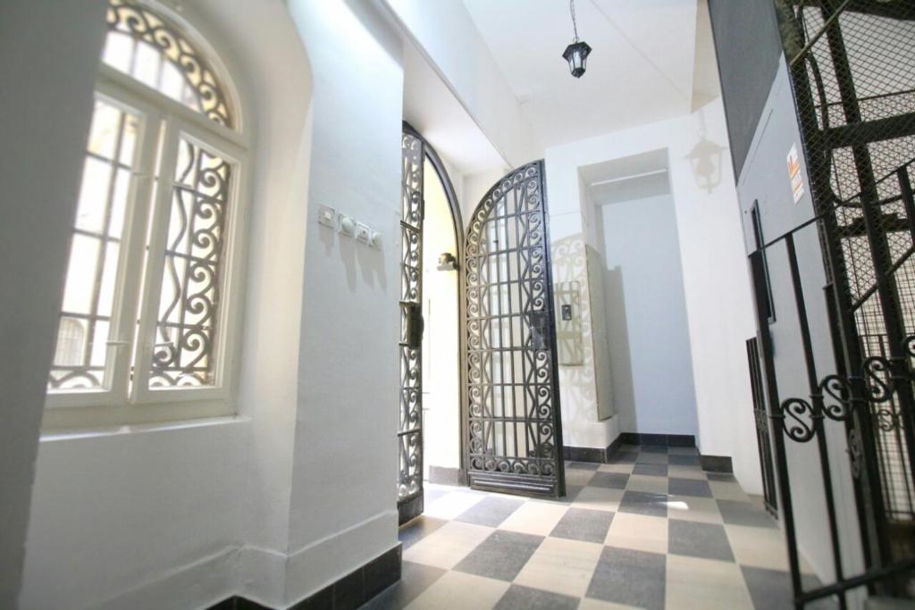 een hal met smeedijzeren deuren en een geruite vloer bij Studio Apartman KOCKA in Belgrado