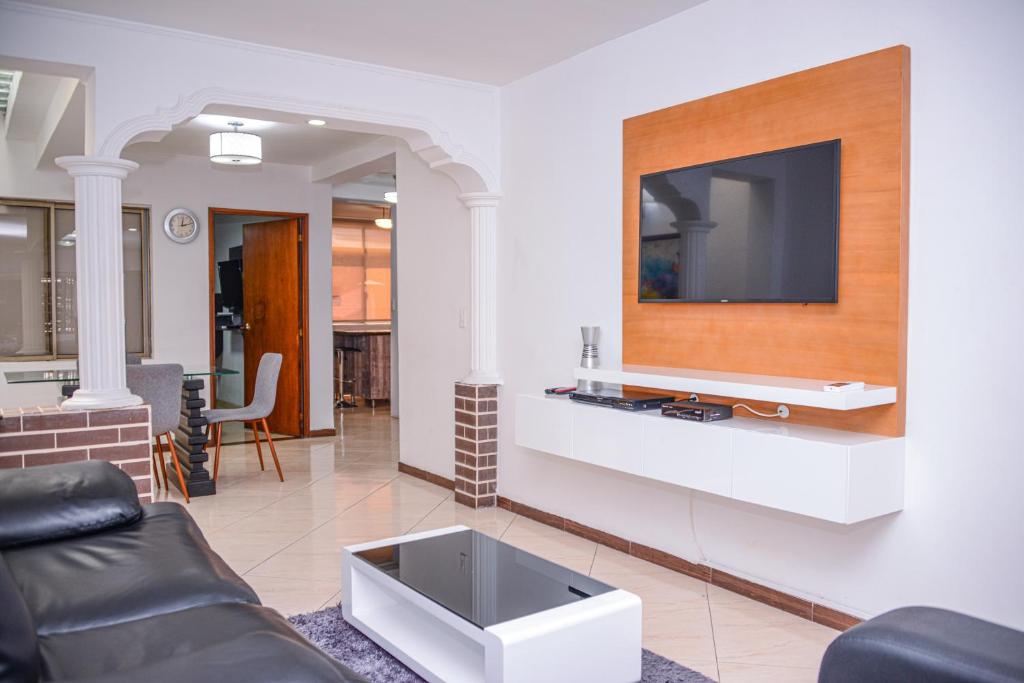 a living room with a couch and a tv on a wall at Poblado Brownstone in Medellín