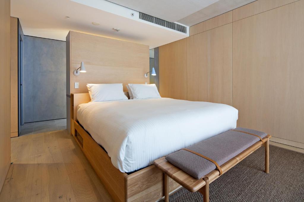 a bedroom with a large bed and a bench at Zara Tower – Luxury Suites and Apartments in Sydney