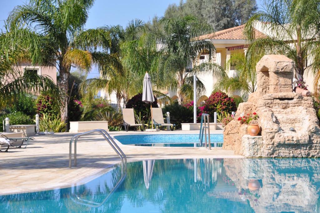 una piscina en un complejo con palmeras en 2 Bed, 2 Bath Apartment In Mandria, en Mandriá