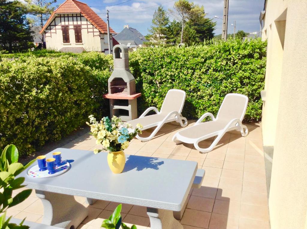 eine Terrasse mit einem Tisch, Stühlen und einem Leuchtturm in der Unterkunft Les Oiseaux in Barneville-Carteret