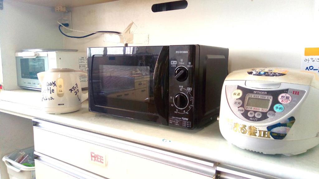 a microwave sitting on a counter next to a food processor at Little Asia Guest House in Naha