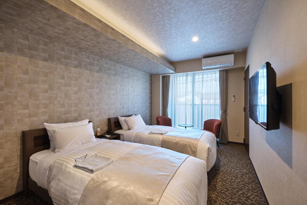 a hotel room with two beds and a television at HOTEL ARROWS ARASHIYAMA in Kyoto