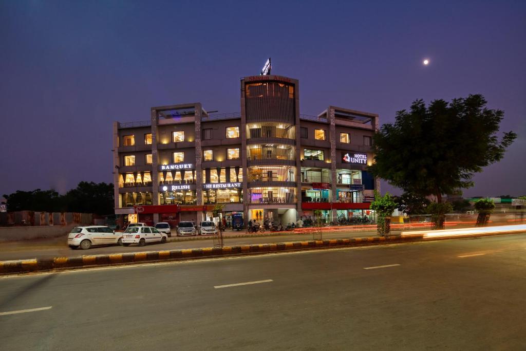 ein großes Gebäude mit davor geparkt in der Unterkunft Hotel Unity in Ahmedabad