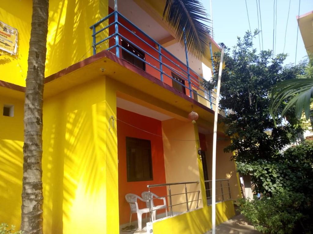 a yellow and red house with a balcony at Shiva Shanti Guest House in Arambol