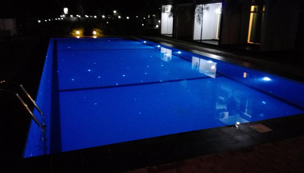 Samwill Holiday Resort في كاتاراغاما: مسبح ازرق في الليل مع اناره