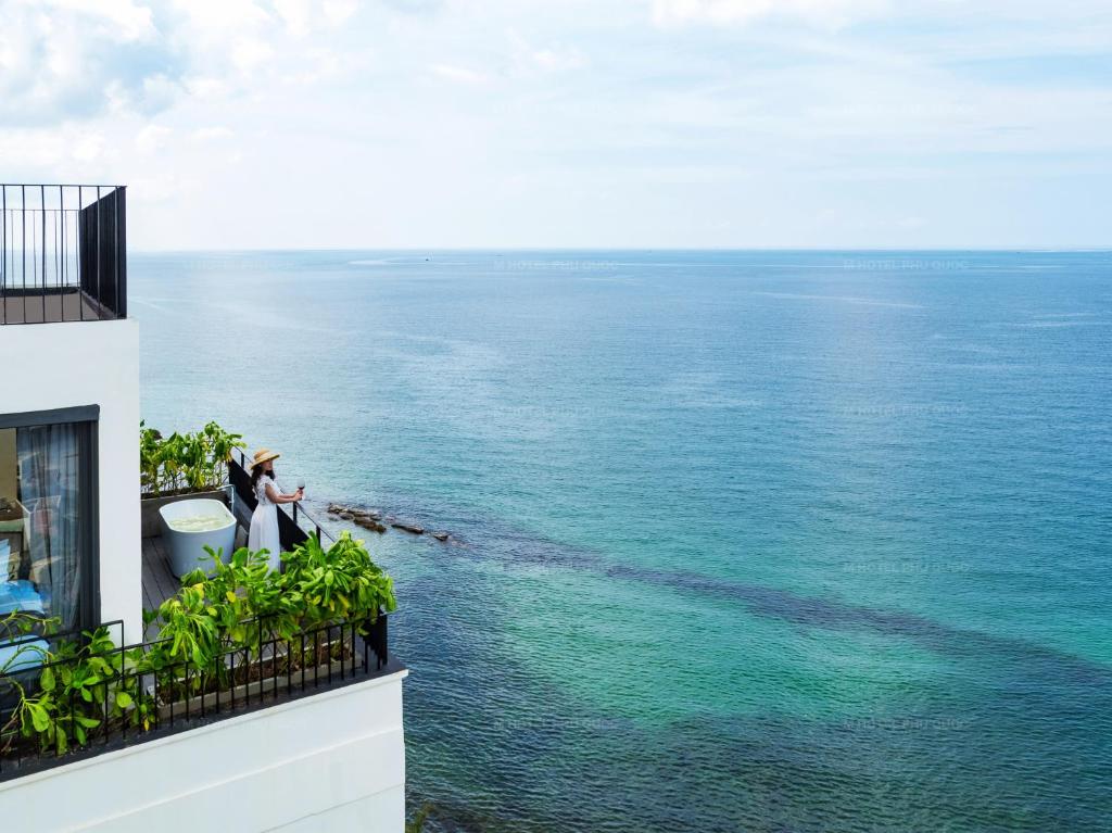 M Hotel Phu Quoc في فو كووك: شخصان يقفان على شرفة تطل على المحيط
