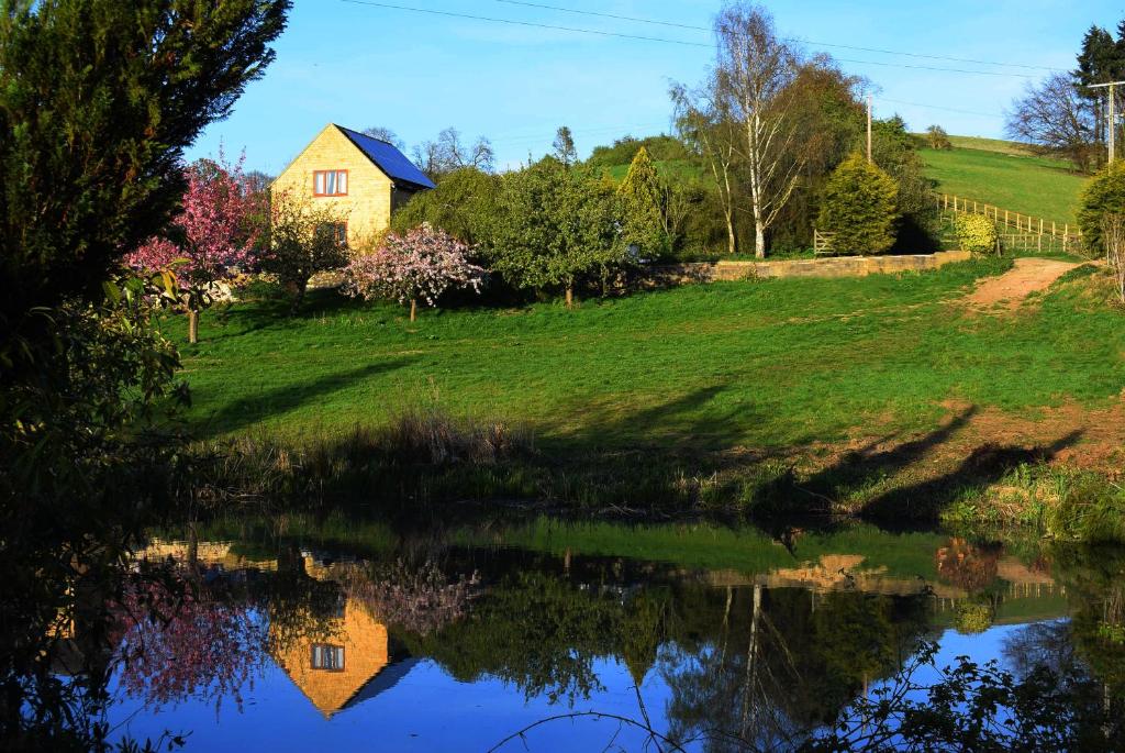 una casa sentada en una colina junto a un estanque en Badgers Sett, en Chipping Campden