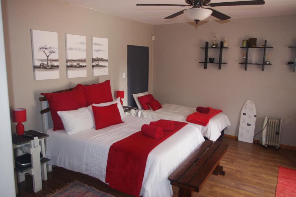 1 dormitorio con 1 cama grande con almohadas rojas en Triginta en Bloemfontein