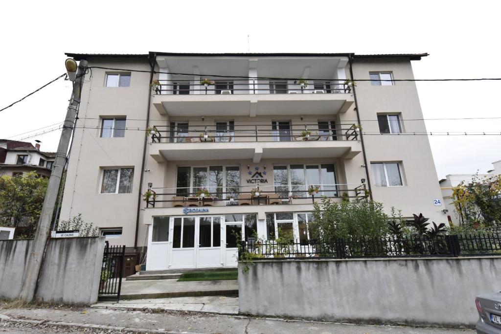 Un grand bâtiment blanc avec balcon est disponible. dans l'établissement Vila Victoria, à Râmnicu Vâlcea