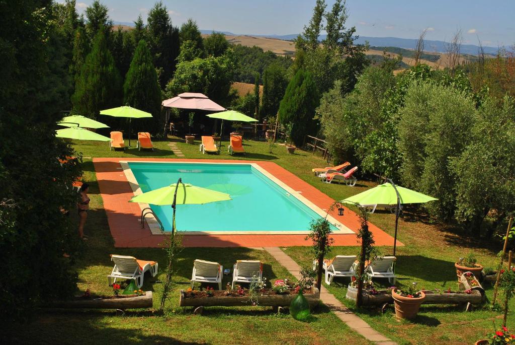 einen Pool mit Stühlen und Sonnenschirmen in der Unterkunft Agriturismo la Nicchia in Castelnuovo Berardenga